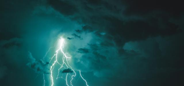 a lightning bolt striking over a city at night by Theo Tab courtesy of Unsplash.